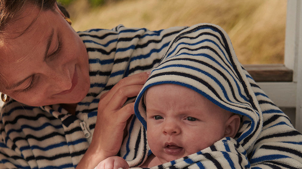Nyfödd baby insvept i randig handduk med huva