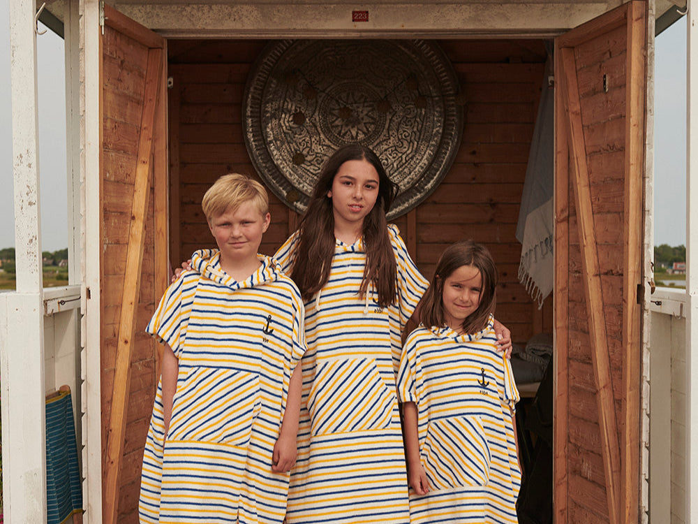 Barn i solskydd och badponcho vid badhuset