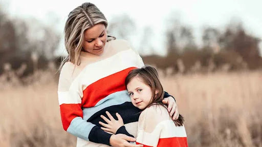 Mamma och dotter i randiga stickade tröjor på ett fält