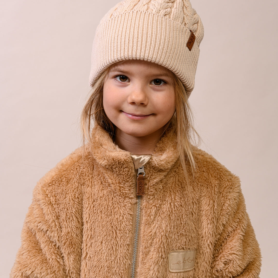 Barn i stickad mössa och teddyfleece