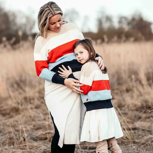 Mamma och dotter i randiga stickade tröjor på ett fält
